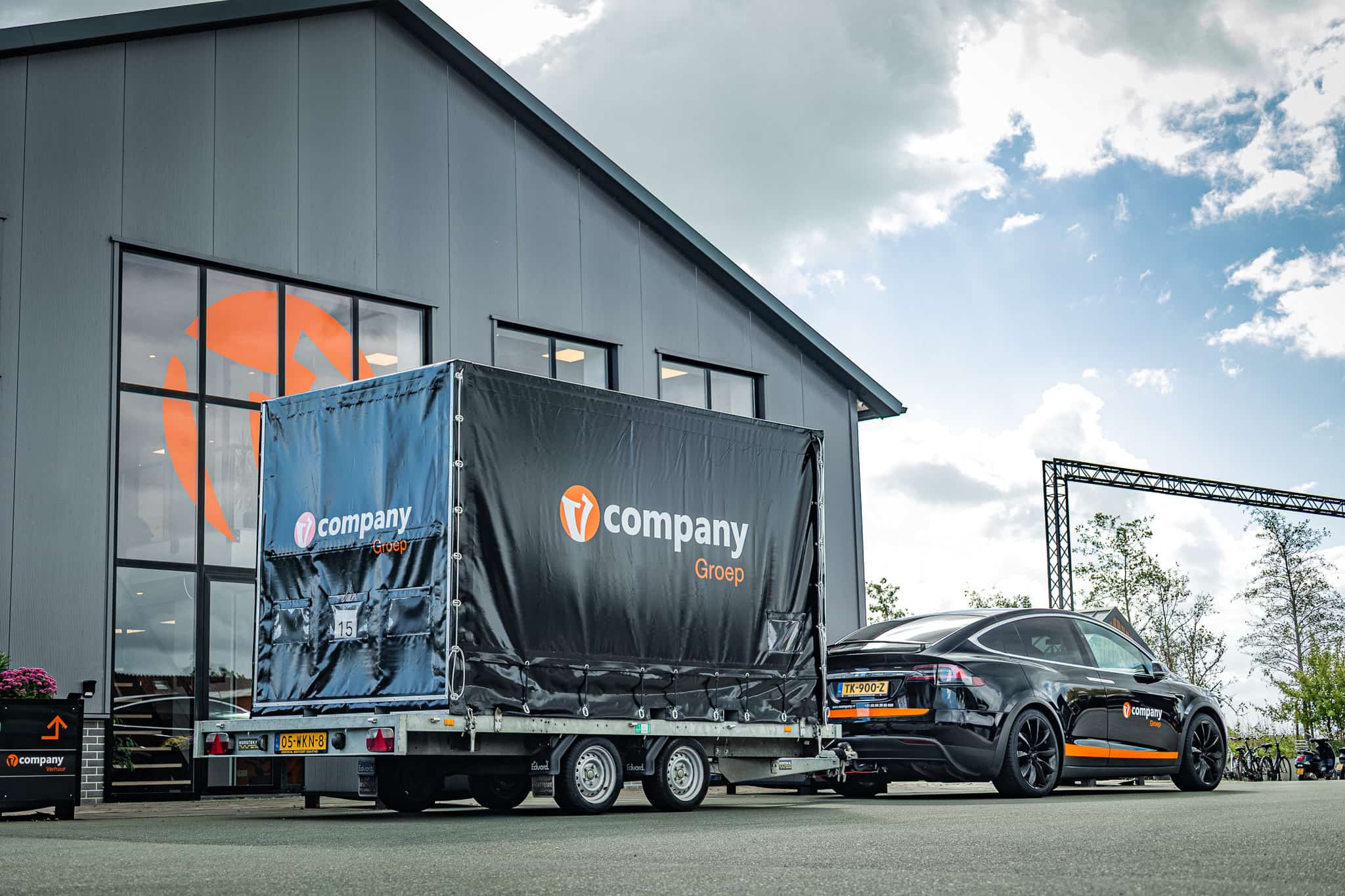 Tesla met aanhanger voor het gebouw